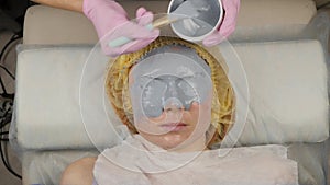 Beautician applying mud mask for woman face in the spa salon. facial rejuvenation procedure, spa treatments