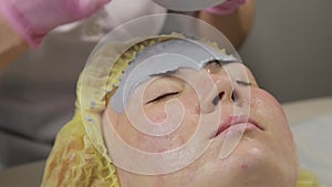 Beautician applying mud mask for woman face in the spa salon. facial rejuvenation procedure, spa treatments