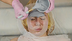 Beautician applying mud mask for woman face in the spa salon. facial rejuvenation procedure, spa treatments. 4K