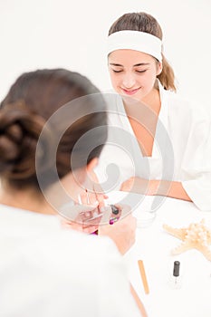 Beautician applying nail varnish to female clients nails