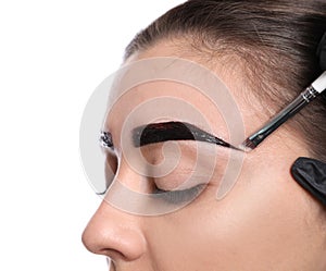 Beautician applying tint during eyebrows correction procedure on white background, closeup