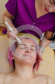 Beautician is cleaning patient`s face, electrophoresis