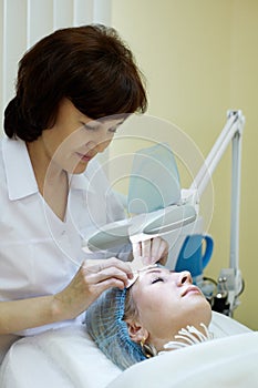 Beautician cleans facial skin of woman