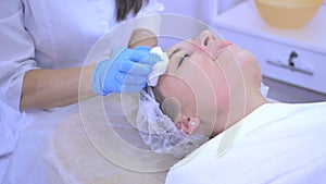 Beautician cleans female`s face skin in beauty clinic