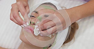 beautician cleanses skin of beautiful woman with napkin.