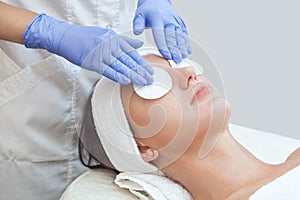 Beautician cleanses the skin on the face from acne and blackheads on the woman`s face in a beauty salon.Treatment of problem skin