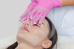 Beautician cleanses the skin of a woman before a facial treatment in a beauty salon. Skin and spa treatments. Cosmetology and