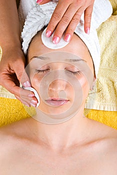 Beautician cleansing young woman face