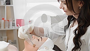 The beautician demonstrates professional skills during the facial peeling procedure. In the beauty clinic, a young woman