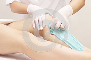 Beautician depilating young womans legs with liquid sugar in spa center. depilation of legs