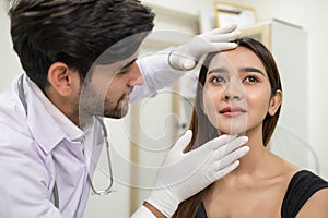 Beautician doctor wear glove touch female face and check skin condition before plastic surgery in the beauty clinic. Woman going