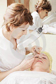 Beautician does eyebrows tweezing procedure