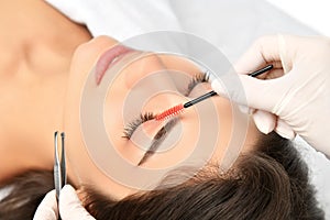 Beautician doing permanent eyebrows makeup. Closeup composition of beautiful woman face with thick brows In beauty salon