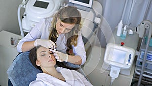 Beautician doing permanent makeup for eyebrows in beauty salon