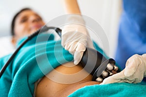 Beautician doing ultrasound cavitation procedure in woman& x27;s abdominal region