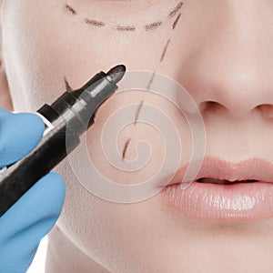 Beautician draw correction lines on woman face