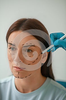 Beautician drawing lines on a womans face