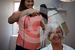 Beautician drying senior woman hair