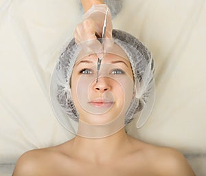 Beautician examining the face of a young female client at spa salon. face cleaning, Una cuchara. Professional photo