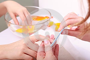 Beautician filing nails of woman. Beauty salon.