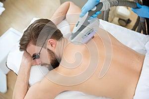 Beautician giving men laser epilation