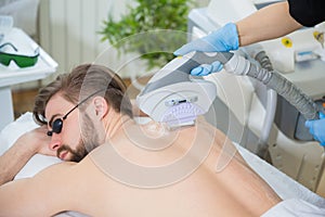 Beautician giving men laser epilation