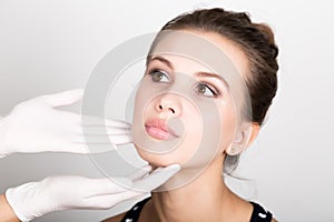 Beautician hand's examining beautiful young female face.