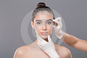 Beautician hands in gloves examining woman face