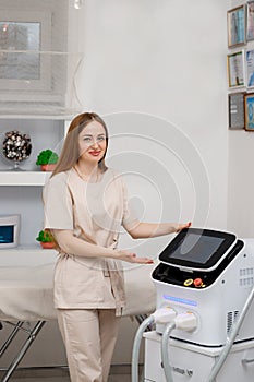 Beautician holding ultrasound device for face and skin lifting procedure and hair removal. Young woman cosmetologist using modern