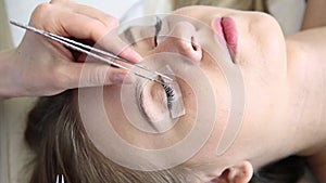 Beautician increases eyelashes for beautiful girl. Eyelash extension procedure