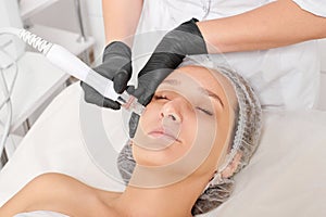 Beautician makes aqua exfoliation for rejuvenation woman face skincare, procedure in beauty salon