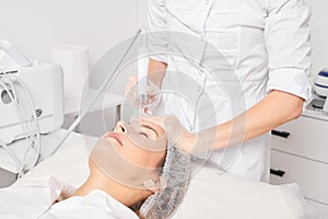 Beautician makes aqua exfoliation for rejuvenation woman face skincare, procedure in beauty salon