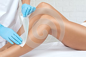 A beautician makes a depilation of a woman`s legs in a beauty salon. Female aesthetic cosmetology
