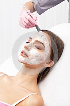 Beautician makes a face mask to rejuvenate the skin. Cosmetology treatment of problem skin on the face and body