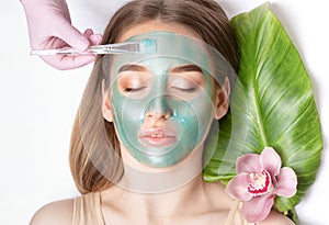 Beautician makes a face mask of a woman to rejuvenate the skin. Cosmetology treatment of problem skin on the face and body