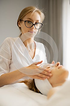 Beautician makes a face massage for a woman