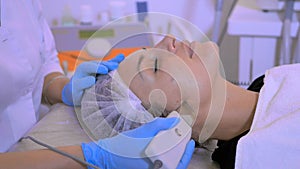 Beautician makes a facial cleaning with electronic equipment