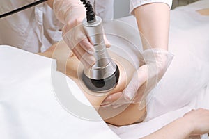 Beautician makes the procedure cavitation of a young beautiful girl. The concept of skin care face and body