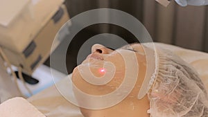 Beautician makes a procedures with medical laser on the female`s face