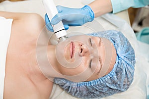 Beautician makes RF-lifting to young woman. The cosmetic procedures for the face. Beauty treatments in the spa salon