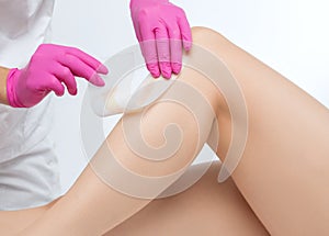 A beautician makes a sugar paste depilation of a woman`s legs in a beauty salon. Female aesthetic cosmetology