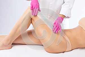 A beautician makes a sugar paste depilation of a woman`s legs in a beauty salon. Female aesthetic cosmetology