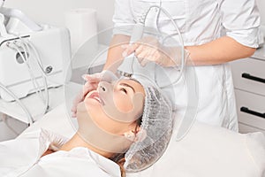 Beautician makes ultrasound skin tightening for rejuvenation woman face using phonophoresis