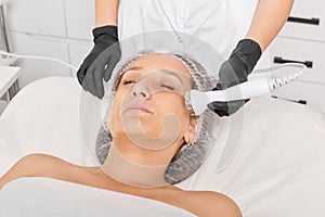 Beautician makes ultrasound skin tightening for rejuvenation woman face using phonophoresis