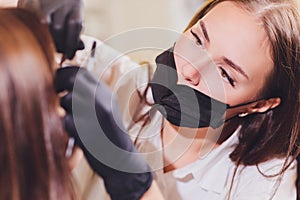 Beautician- makeup artist applies paint henna on previously plucked, design, trimmed eyebrows in a beauty salon in the