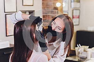 Beautician- makeup artist applies paint henna on previously plucked, design, trimmed eyebrows in a beauty salon in the