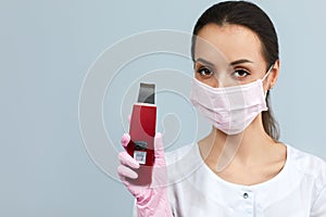 Beautician in mask is holding Ultrasonic scraber.