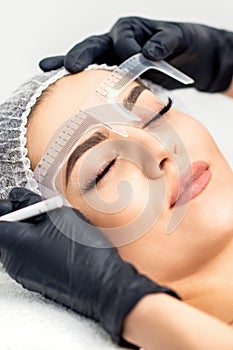 Beautician measuring brows with ruler