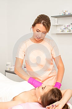 Beautician with a patient during sugaring. The cosmetologist waxes the female armpit.