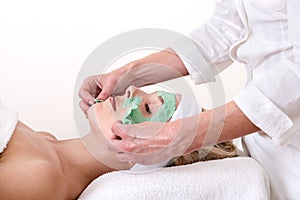 Beautician peeling off a green thalasso beauty facial mask.